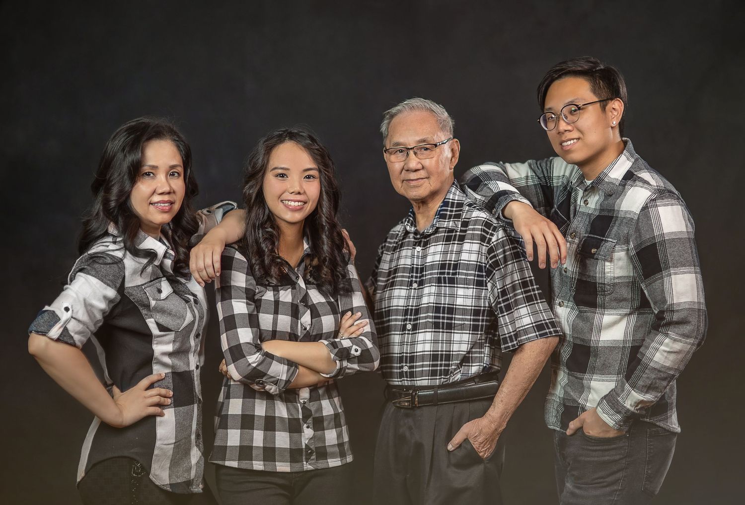A casual family portrait with matching plaid shirts against a dark background.