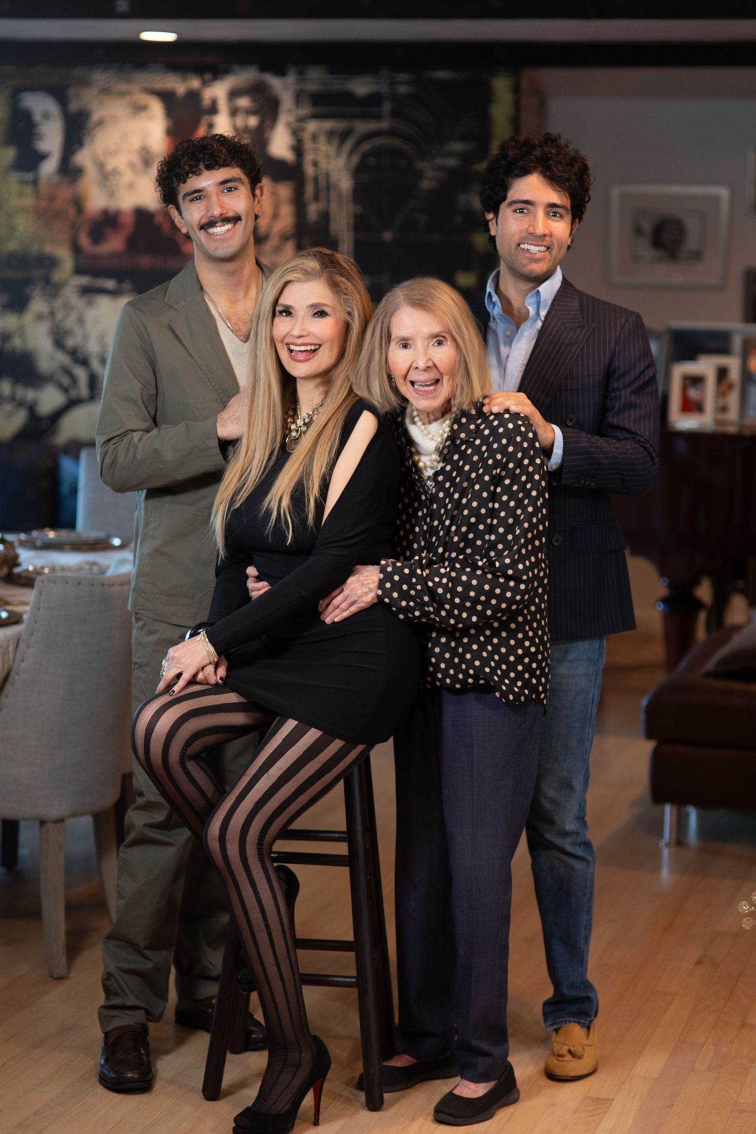 Group photo of four people posing together in a stylish indoor setting.