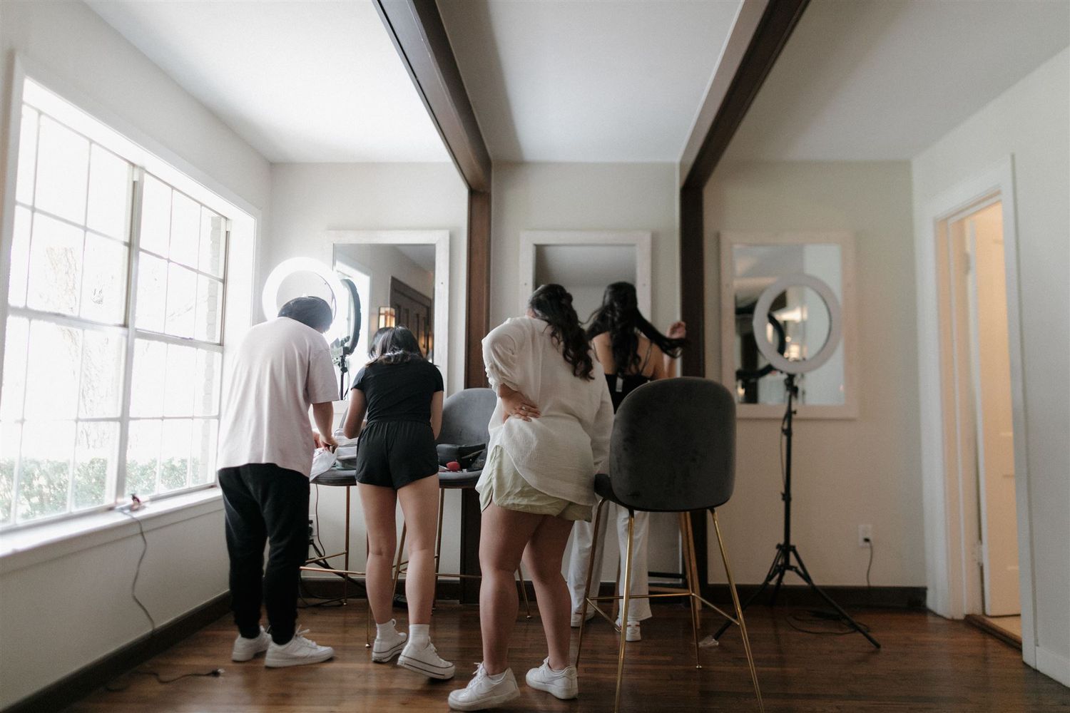 Behind the scenes photo shoot setup with lighting equipment and people in a bright interior space.