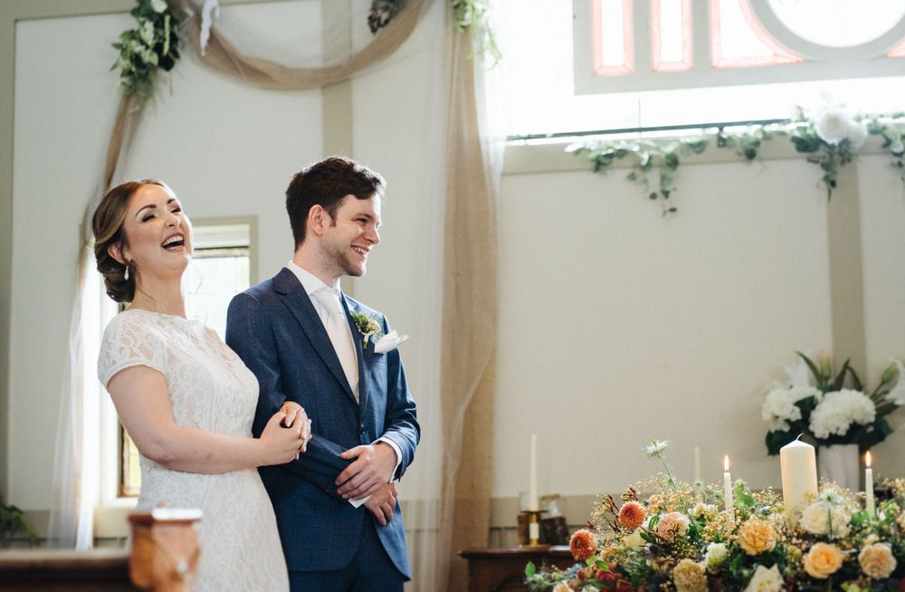 A joyful moment captured during a wedding ceremony under a floral arch.