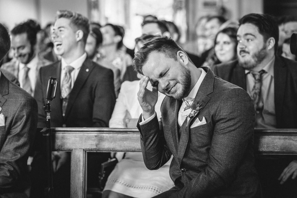 Wedding guests sharing laughter during an emotional ceremony moment.