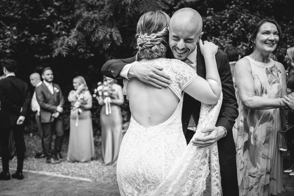 An emotional moment at an outdoor wedding celebration captured in black and white photography.