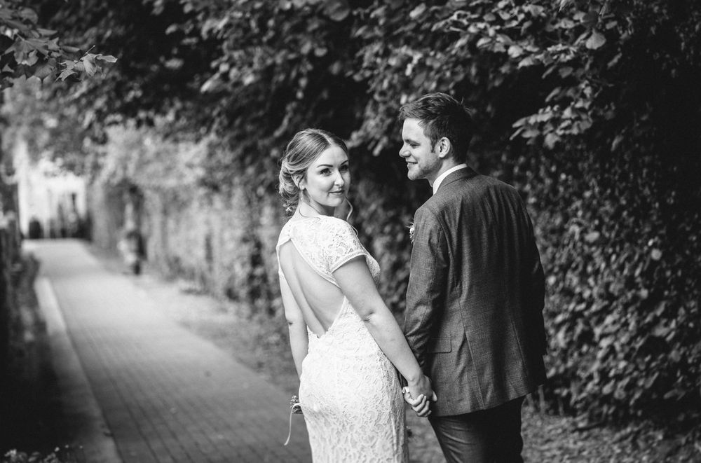 A romantic black and white portrait of newlyweds on a garden path.