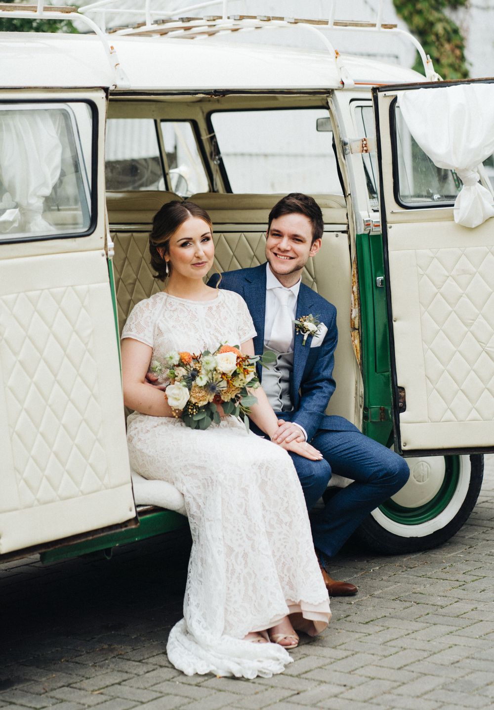 Newlyweds sitting in vintage white and green VW van decorated for their wedding day.