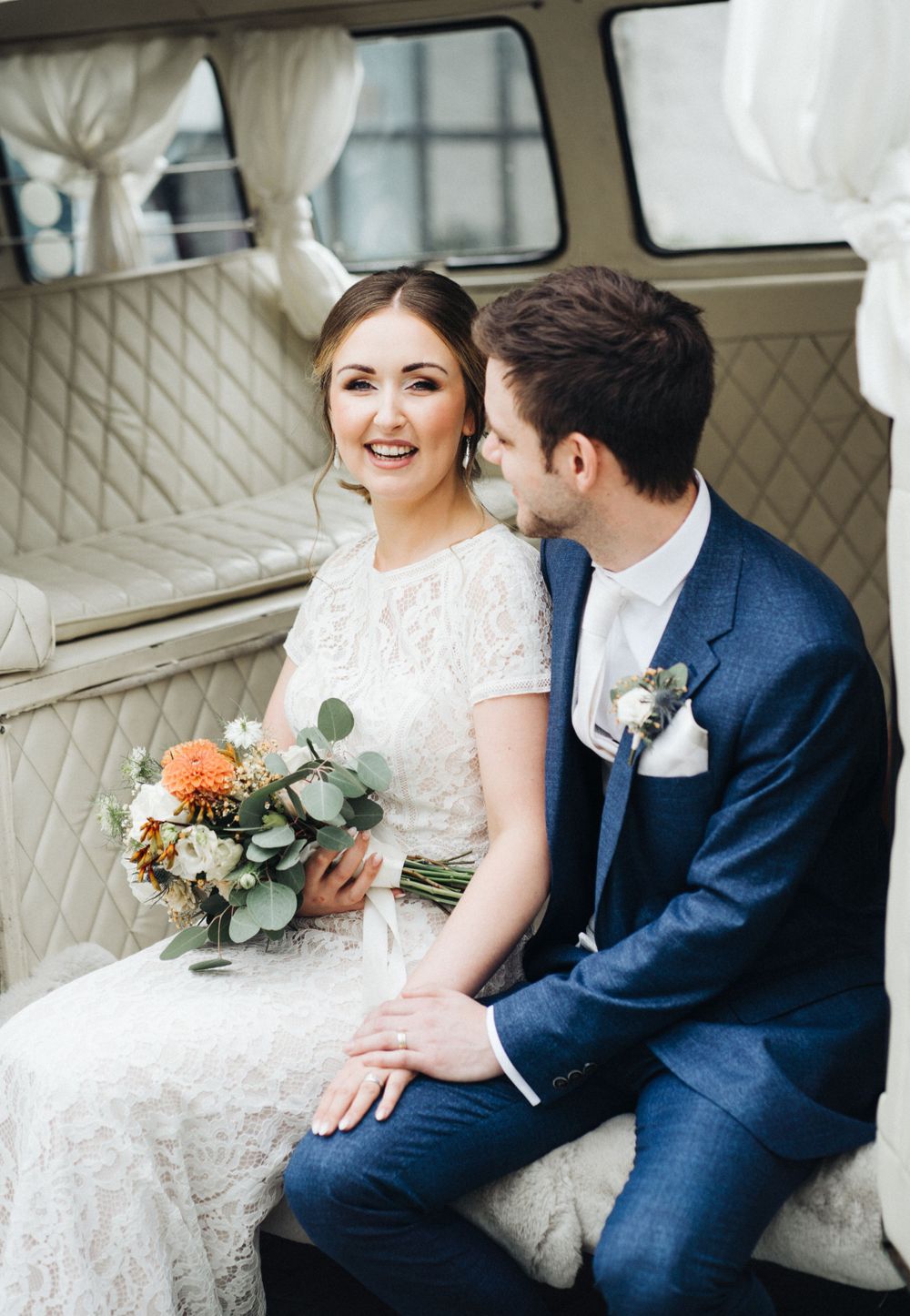 Intimate moment captured of newlyweds inside vintage VW van with elegant wedding details.