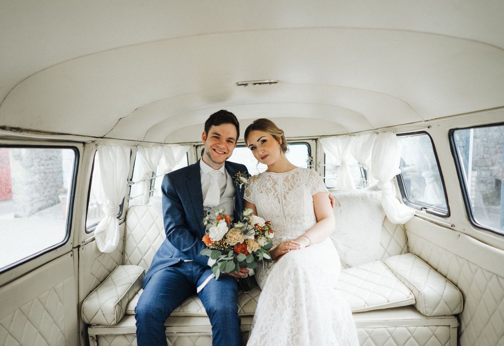 Wedding couple sits together in a classic VW van with white interior.