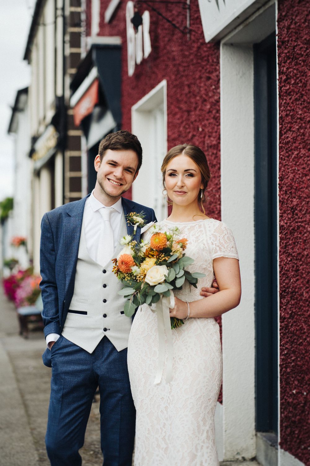 Wedding couple poses in front of a red and white building facade.