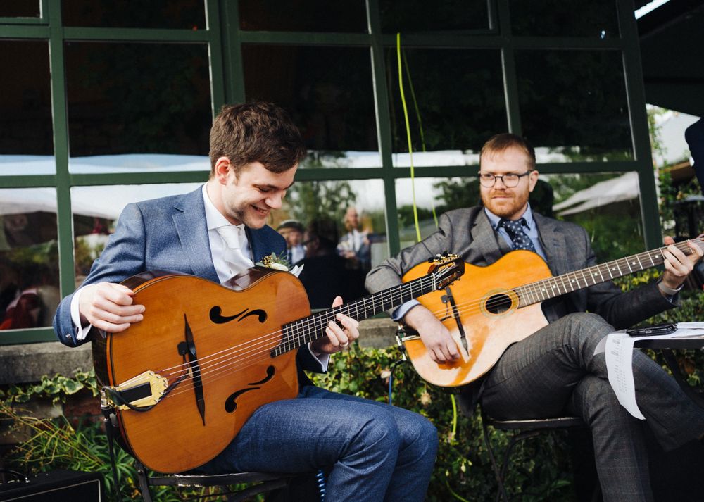 Two musicians playing acoustic guitars outdoors at an event.