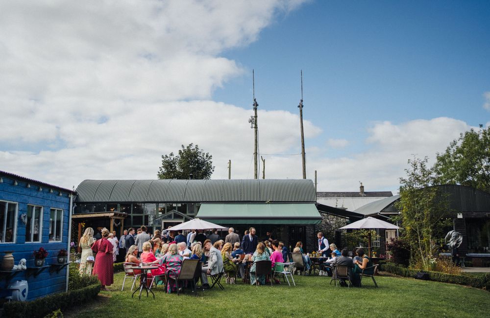 Outdoor wedding reception venue with white tent and guests seated at tables.