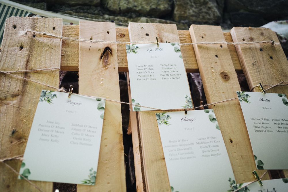 Wedding table place cards and seating arrangements displayed on rustic wooden boards with floral decorations.