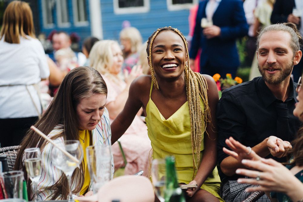 Lively outdoor party scene with guests enjoying drinks and conversation.