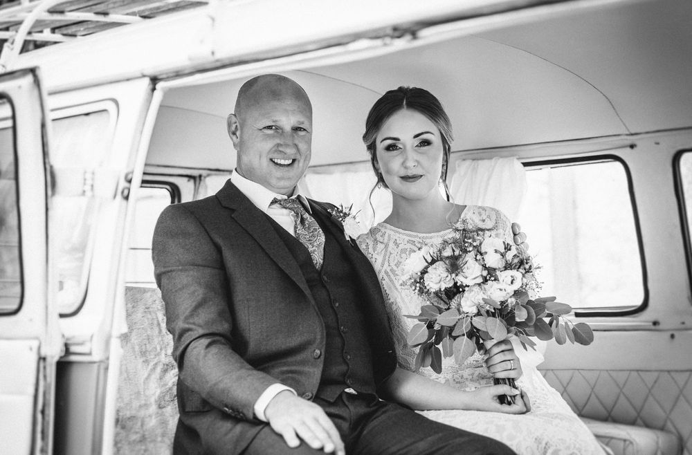 A couple sits inside a vintage van on their wedding day.