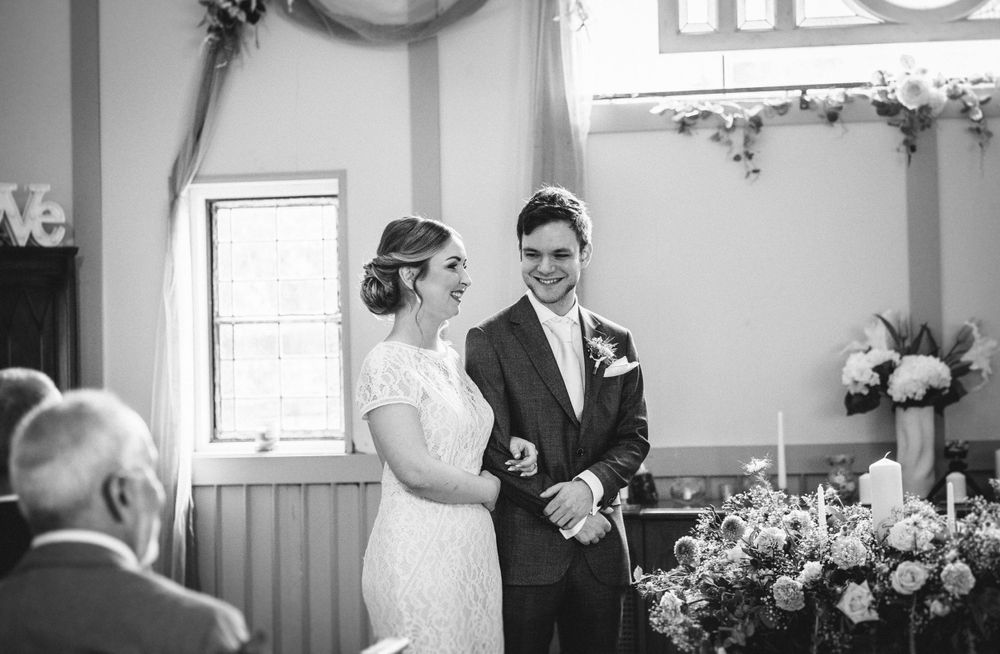 A couple exchanges vows during their wedding ceremony surrounded by floral decorations.