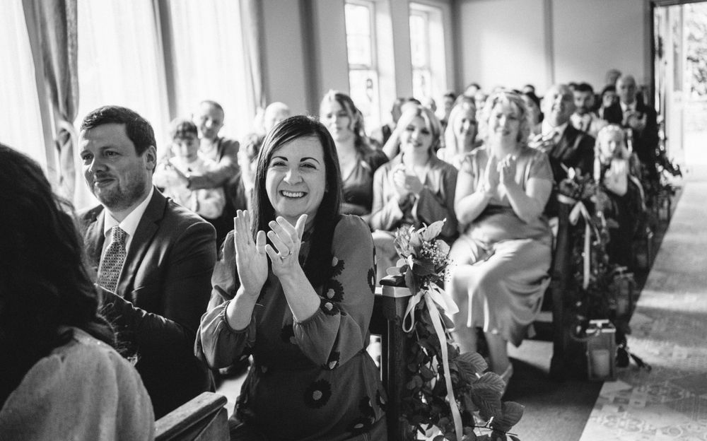 Wedding guests in formal attire reacting emotionally during the ceremony.