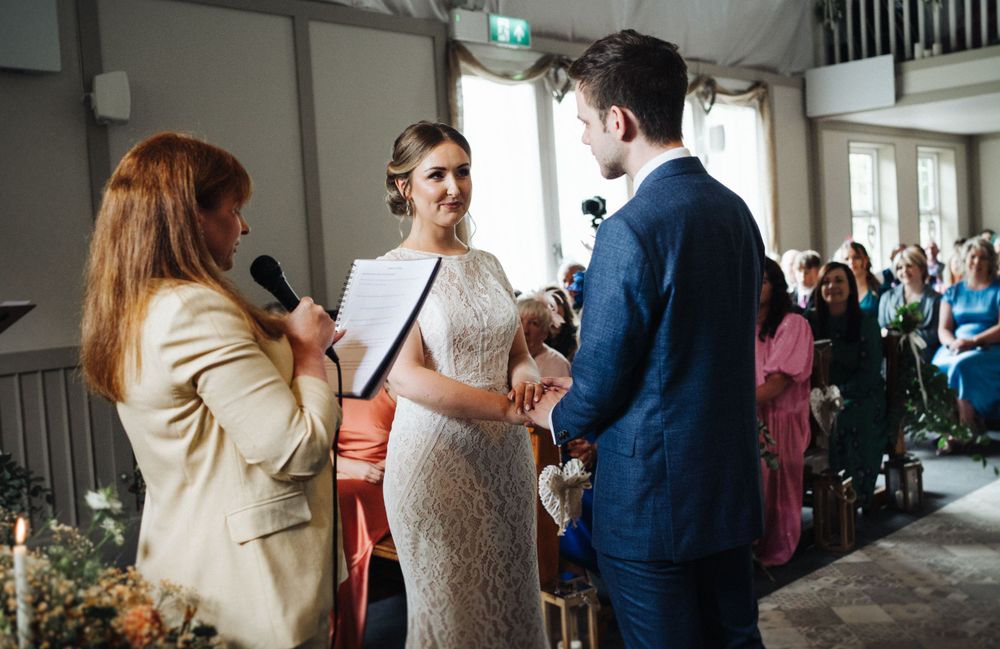 A wedding ceremony in progress with participants in formal attire exchanging vows.