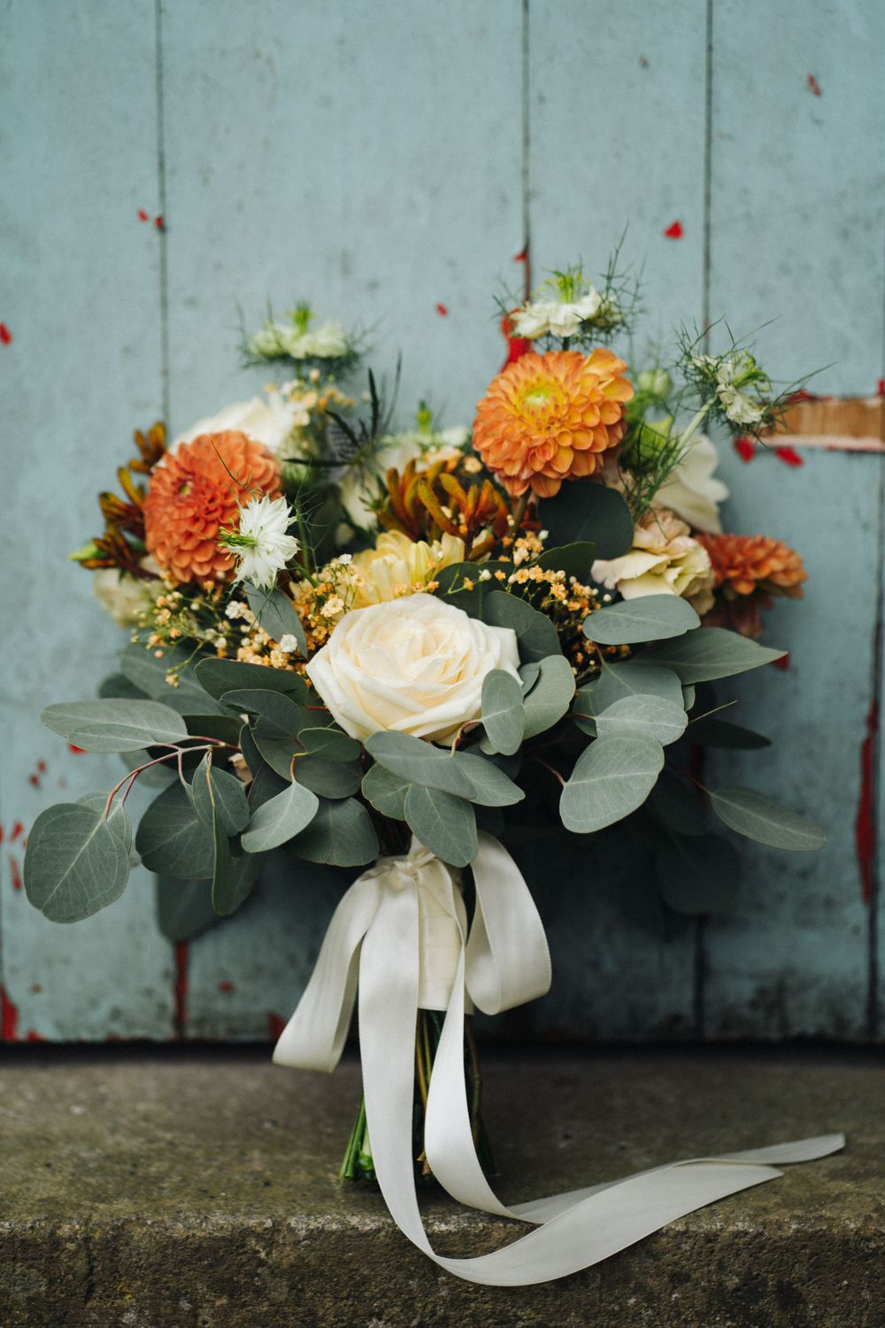 Beautiful autumn wedding bouquet with orange and white flowers tied with a ribbon.