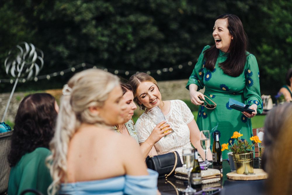 Wedding guests in colorful attire share laughter during an outdoor reception.