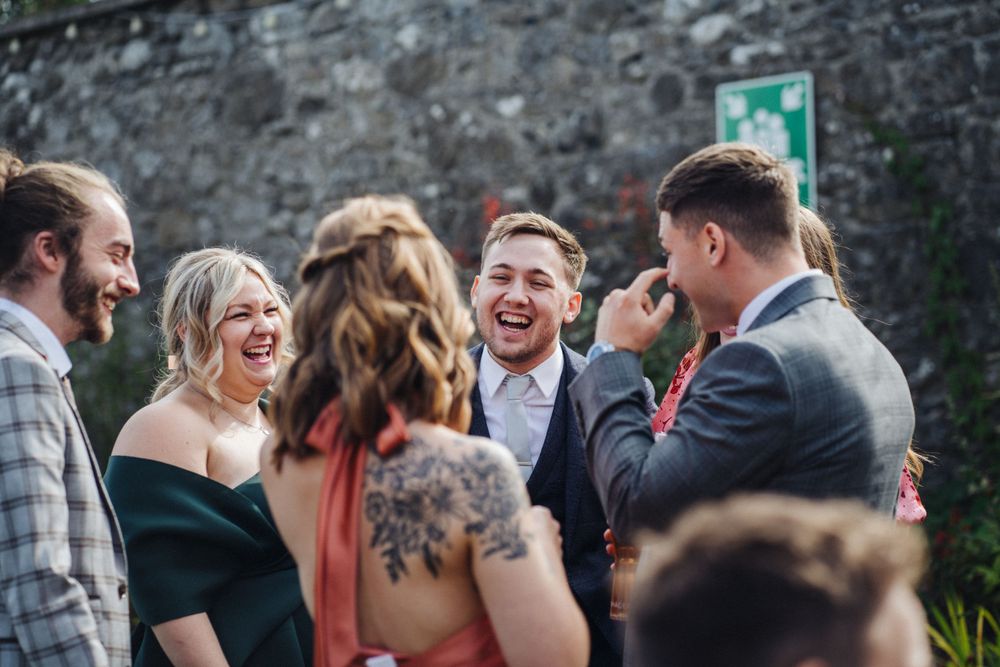 Group of wedding guests laughing and socializing at an outdoor garden party.