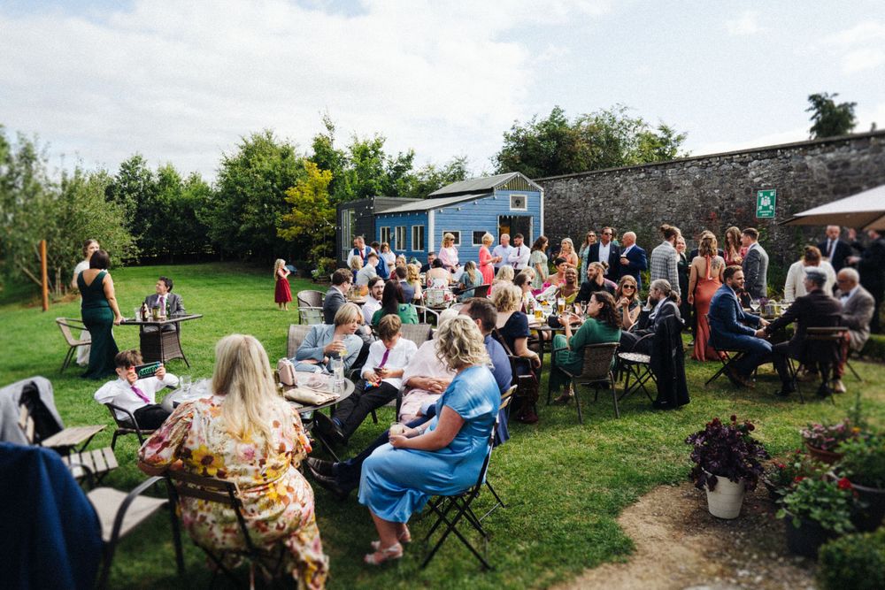Large gathering of wedding guests seated at tables during an outdoor garden reception.