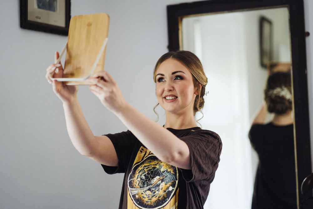 A person in a dark shirt holds up a brown envelope while standing in front of a mirror.