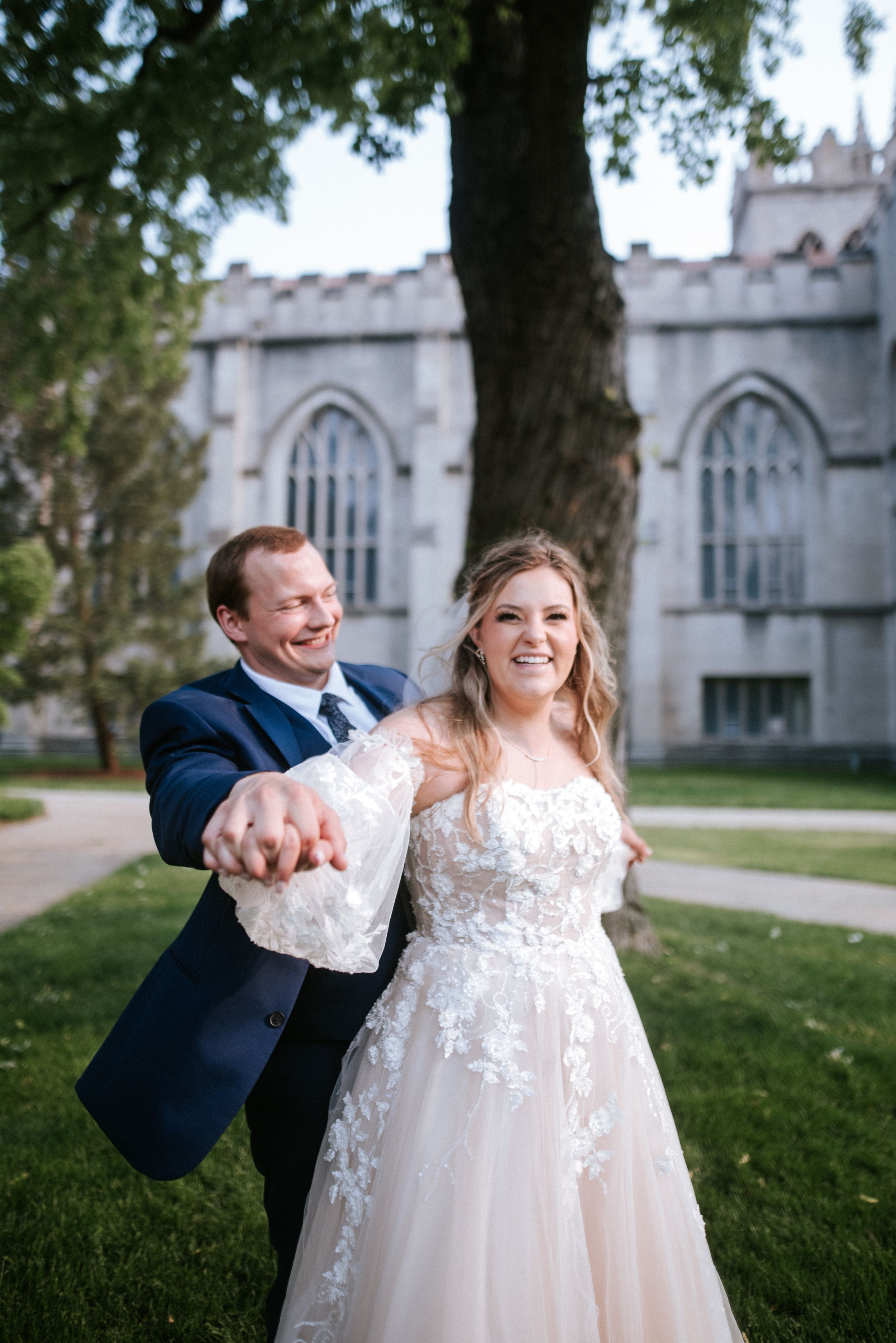 Joyful moment captured outside gothic church building during wedding photoshoot.