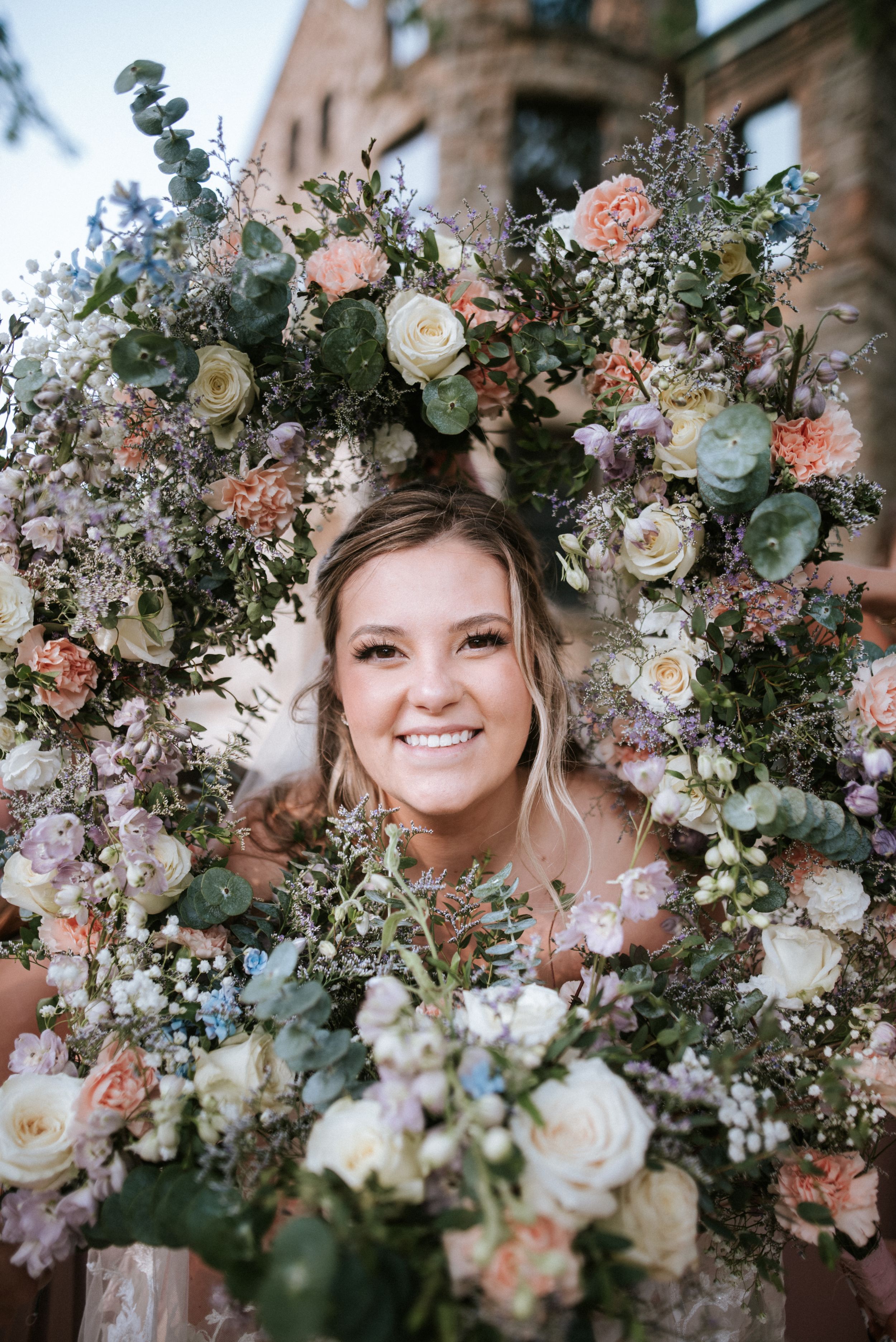 Creative portrait through floral wreath with roses, eucalyptus and baby's breath.