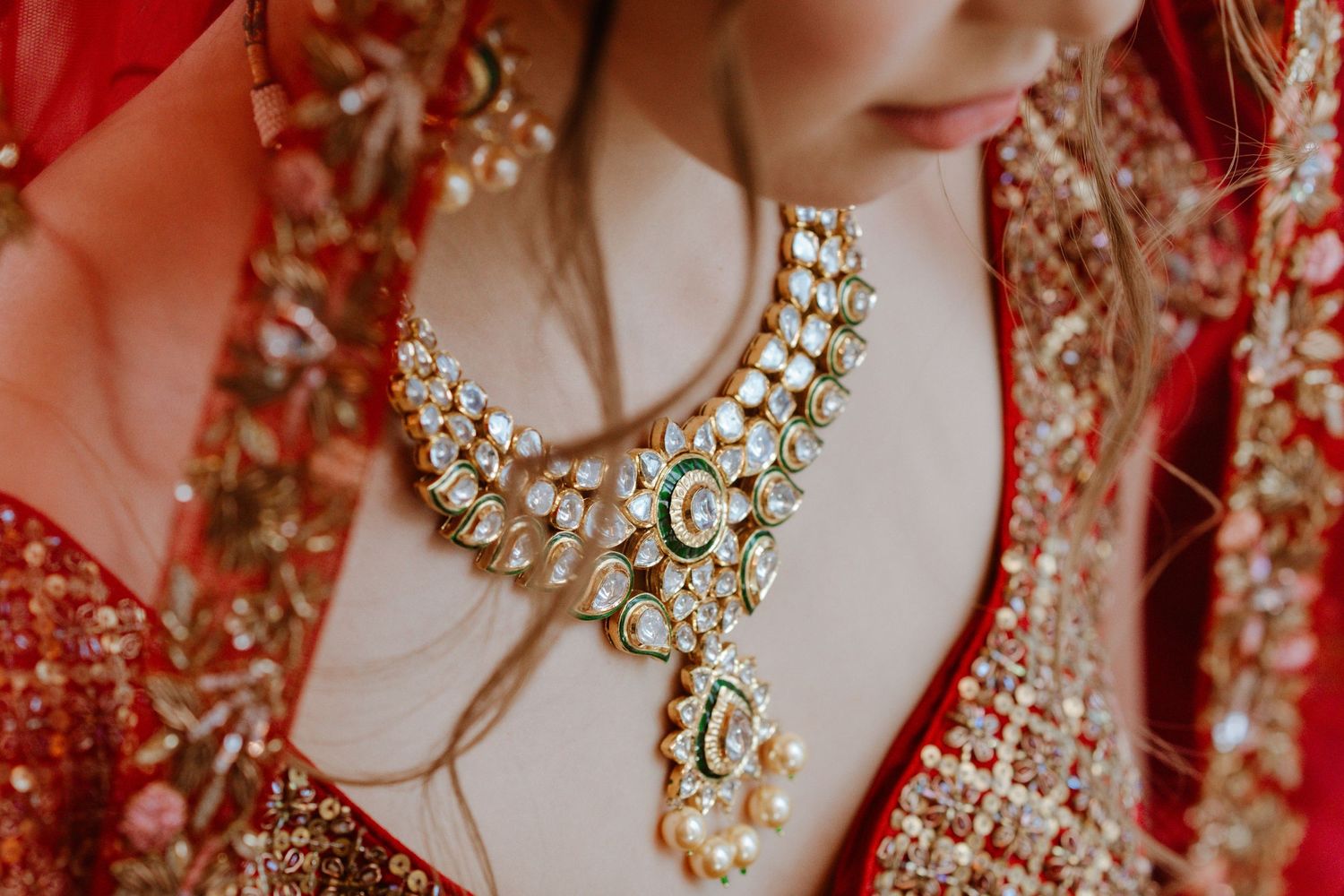 Detailed shots of bridal jewelry featuring kundan necklace and traditional red outfit embroidery.