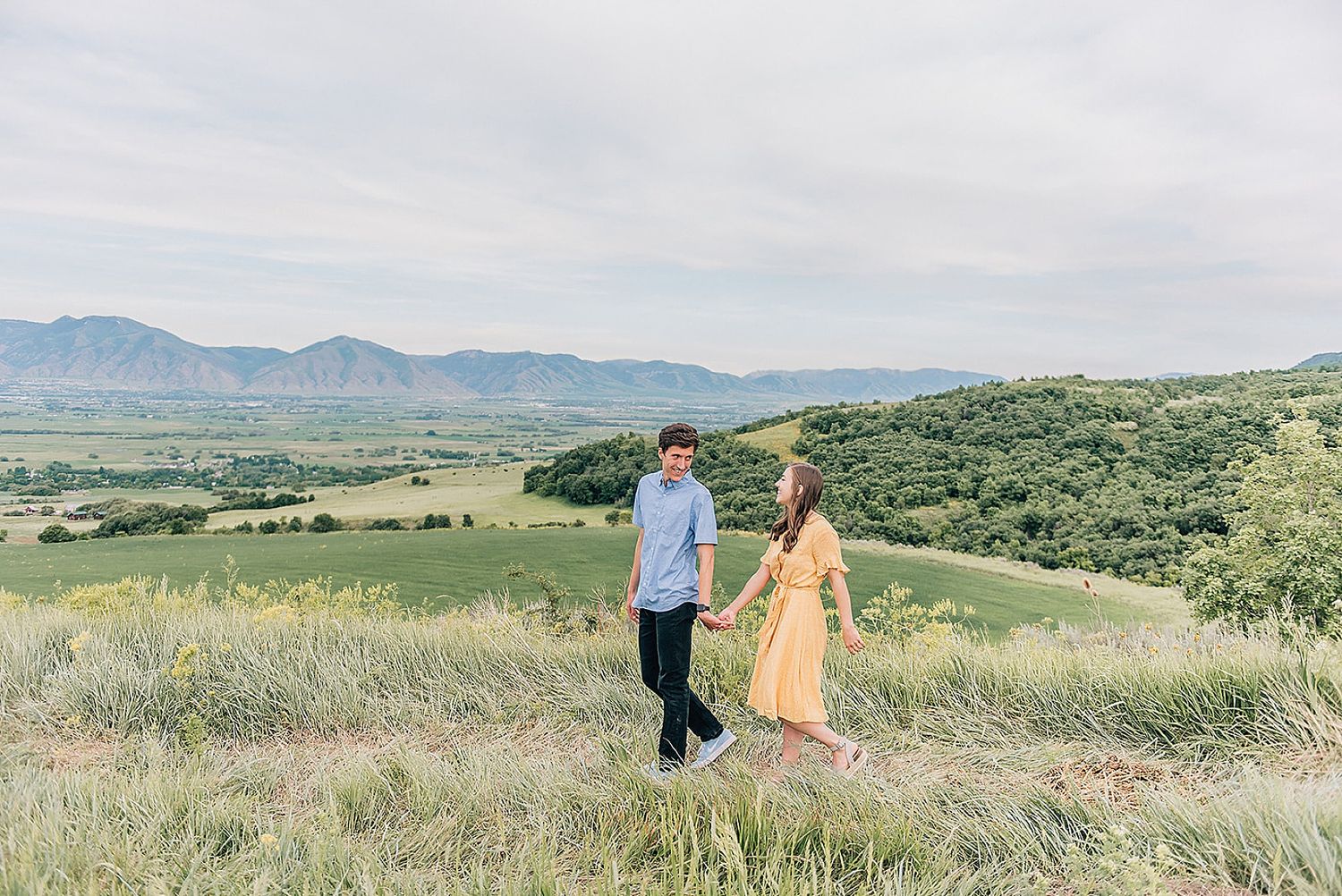 Couple enjoying scenic mountain views while posing in natural meadow setting.