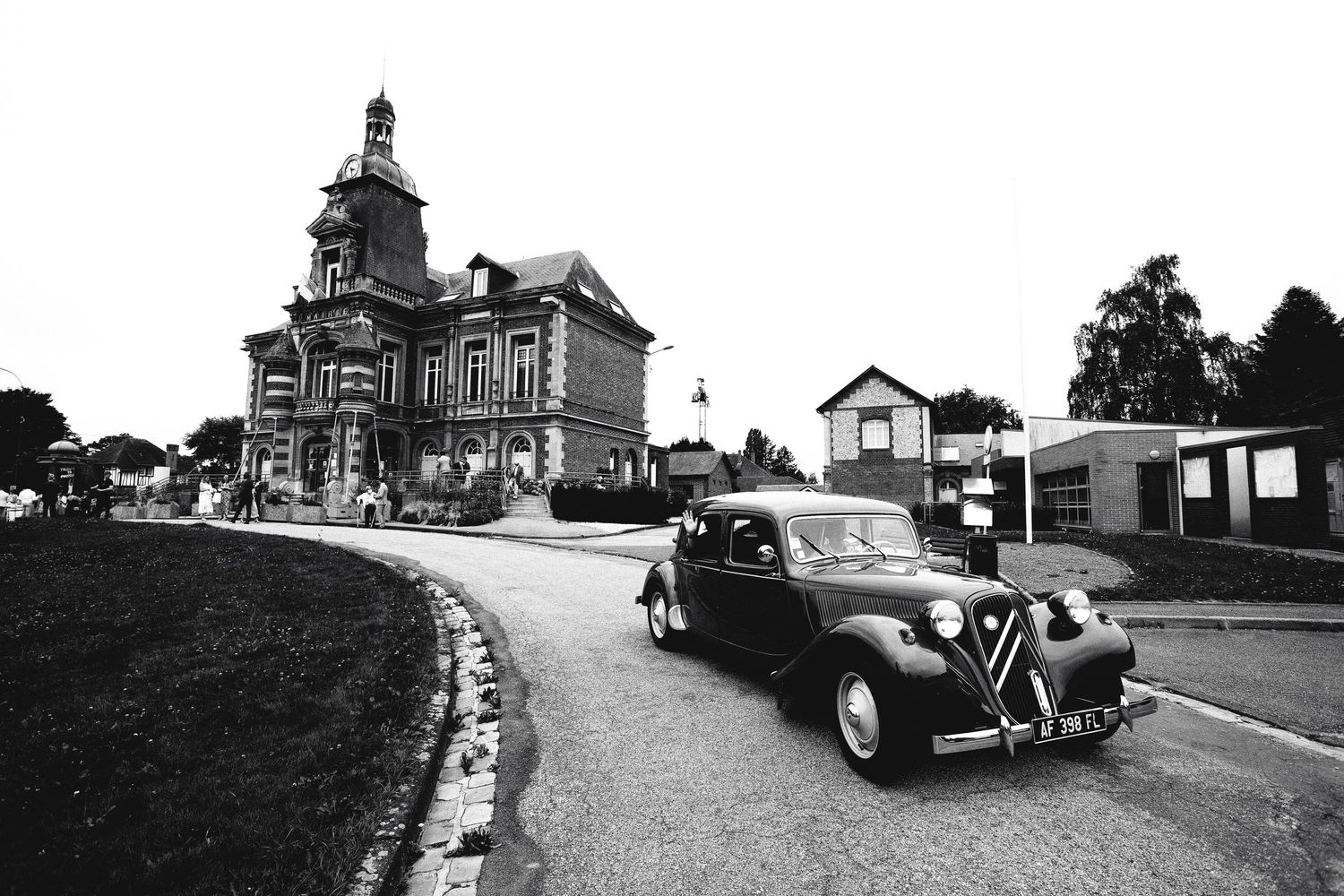 Vintage black and white photo of classic car in front of historic building.