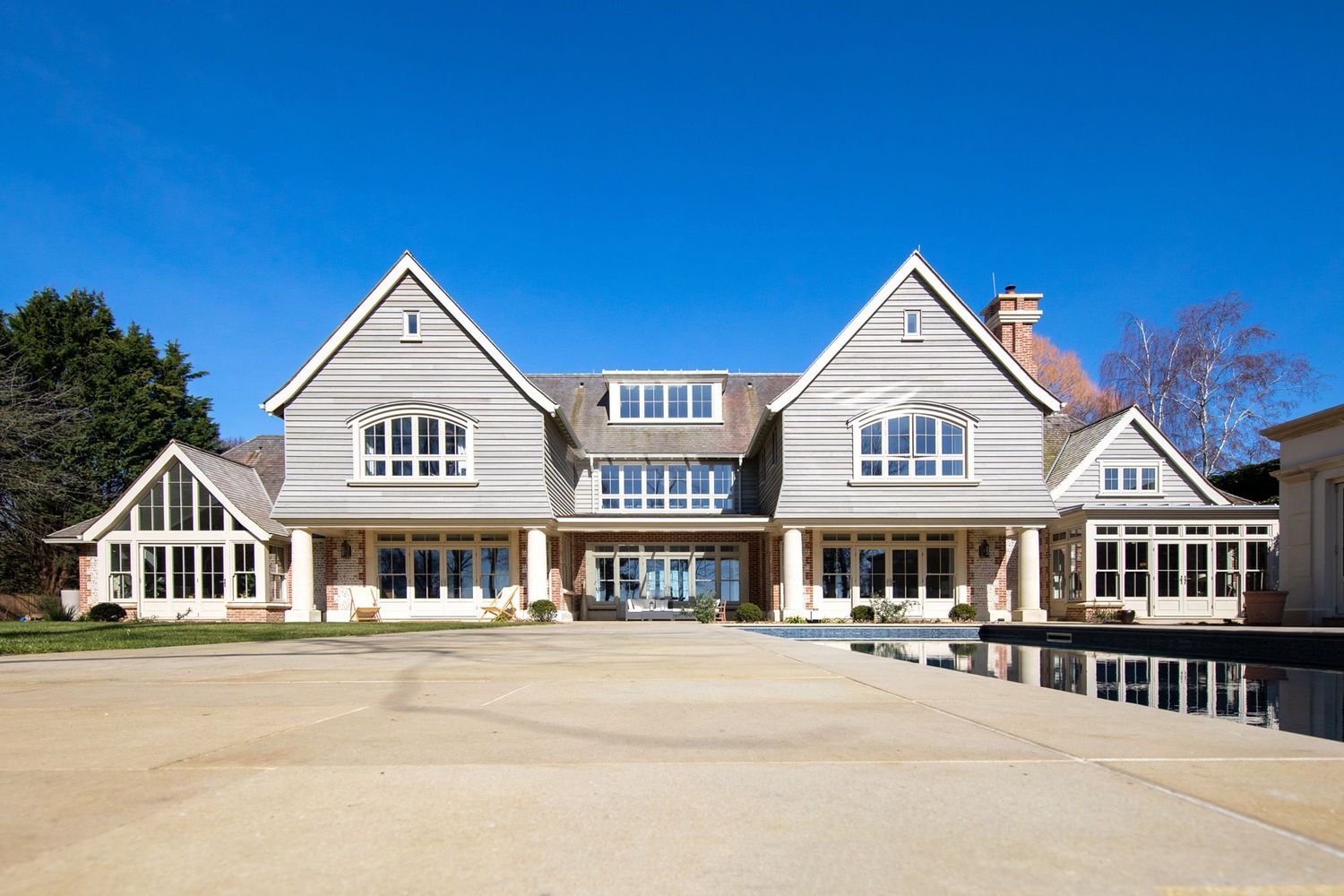 Large coastal-style mansion with symmetrical gables and expansive front facade.