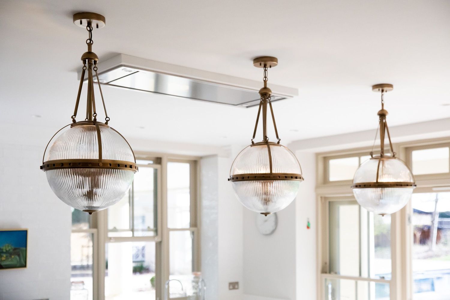 Three vintage-style glass dome pendant lights hanging from a white ceiling with decorative trim.