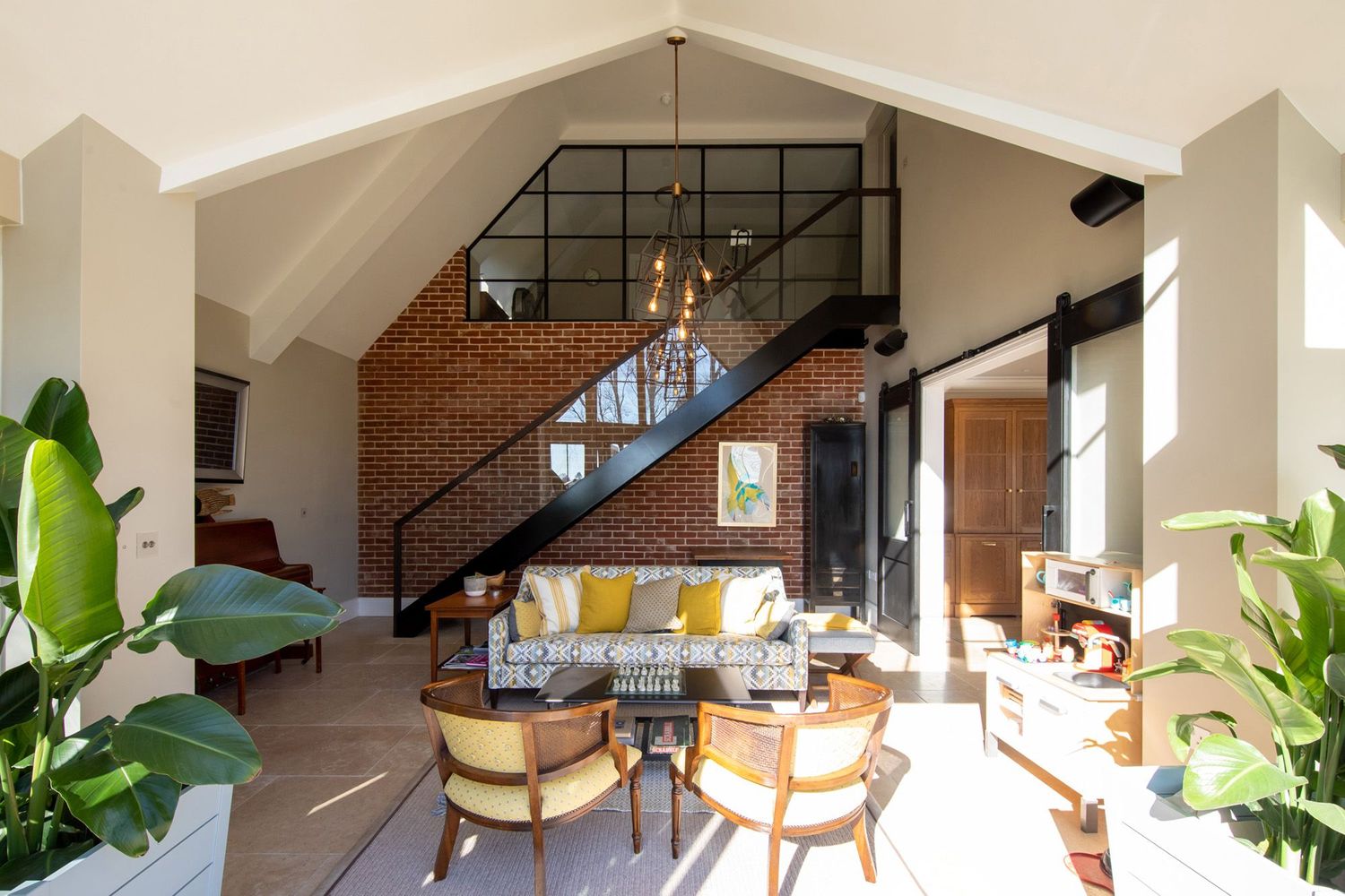 Loft-style living room with exposed brick wall, industrial staircase, and mid-century modern furniture.