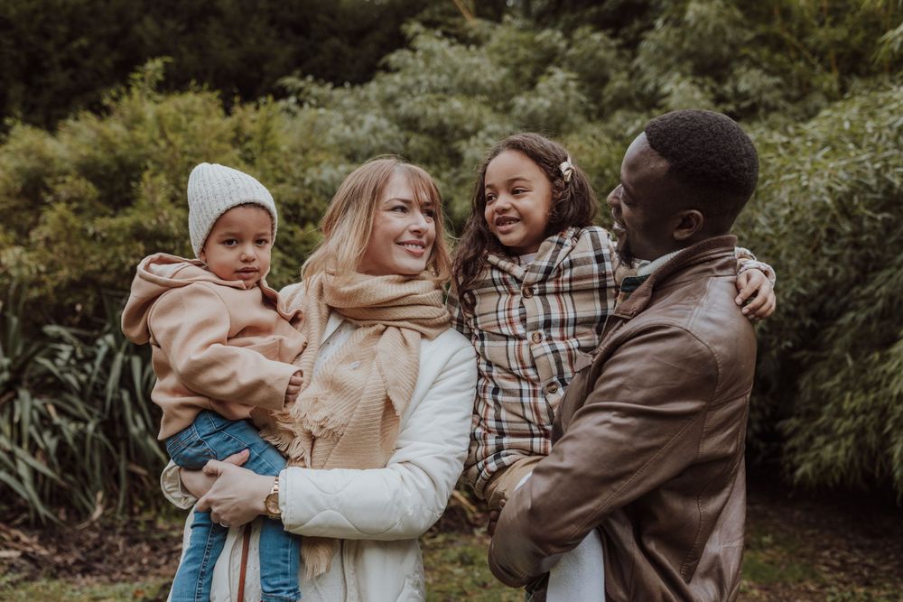 A loving family shares joyful laughter together in an outdoor setting against greenery.