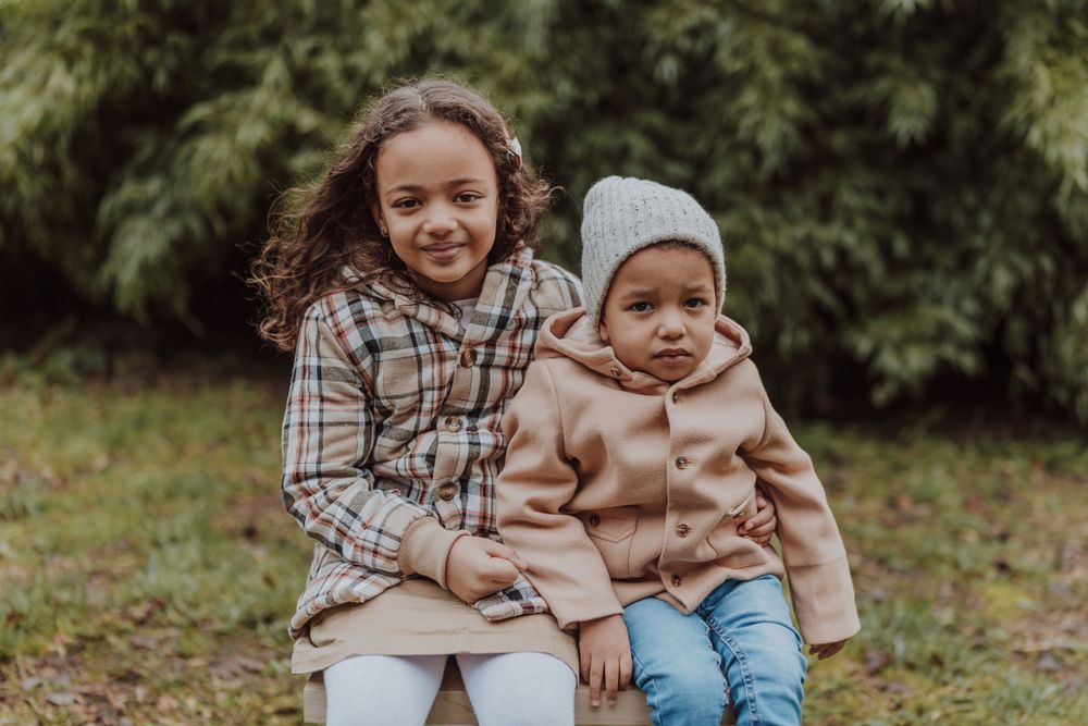 Two siblings share a sweet moment together outdoors on an autumn day.