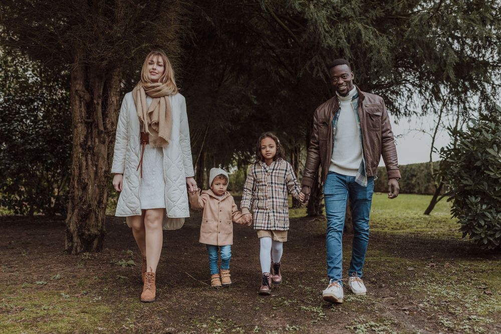 A family of four takes a walk together through a tree-lined path.