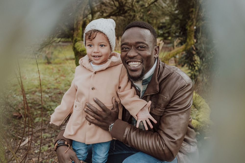 Parent and child share a joyful moment outdoors wearing winter coats.