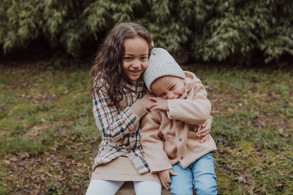 Two children share a playful embrace while sitting together outdoors.