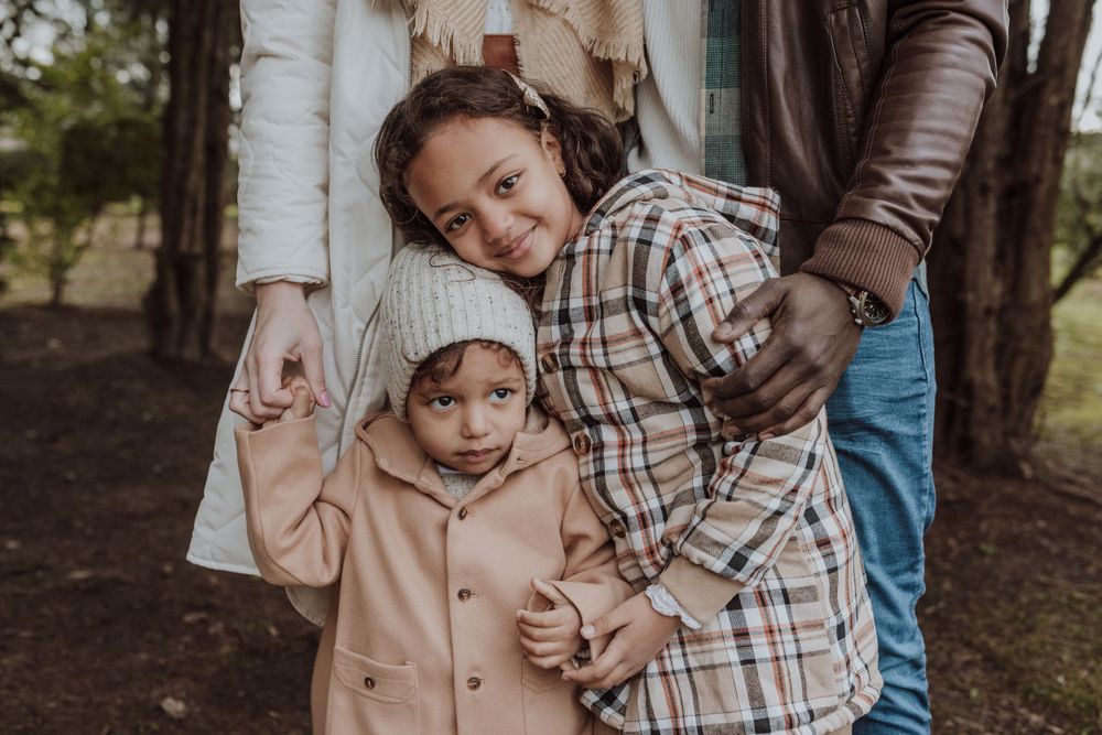 A heartwarming family moment captured in a wooded setting showing natural affection.