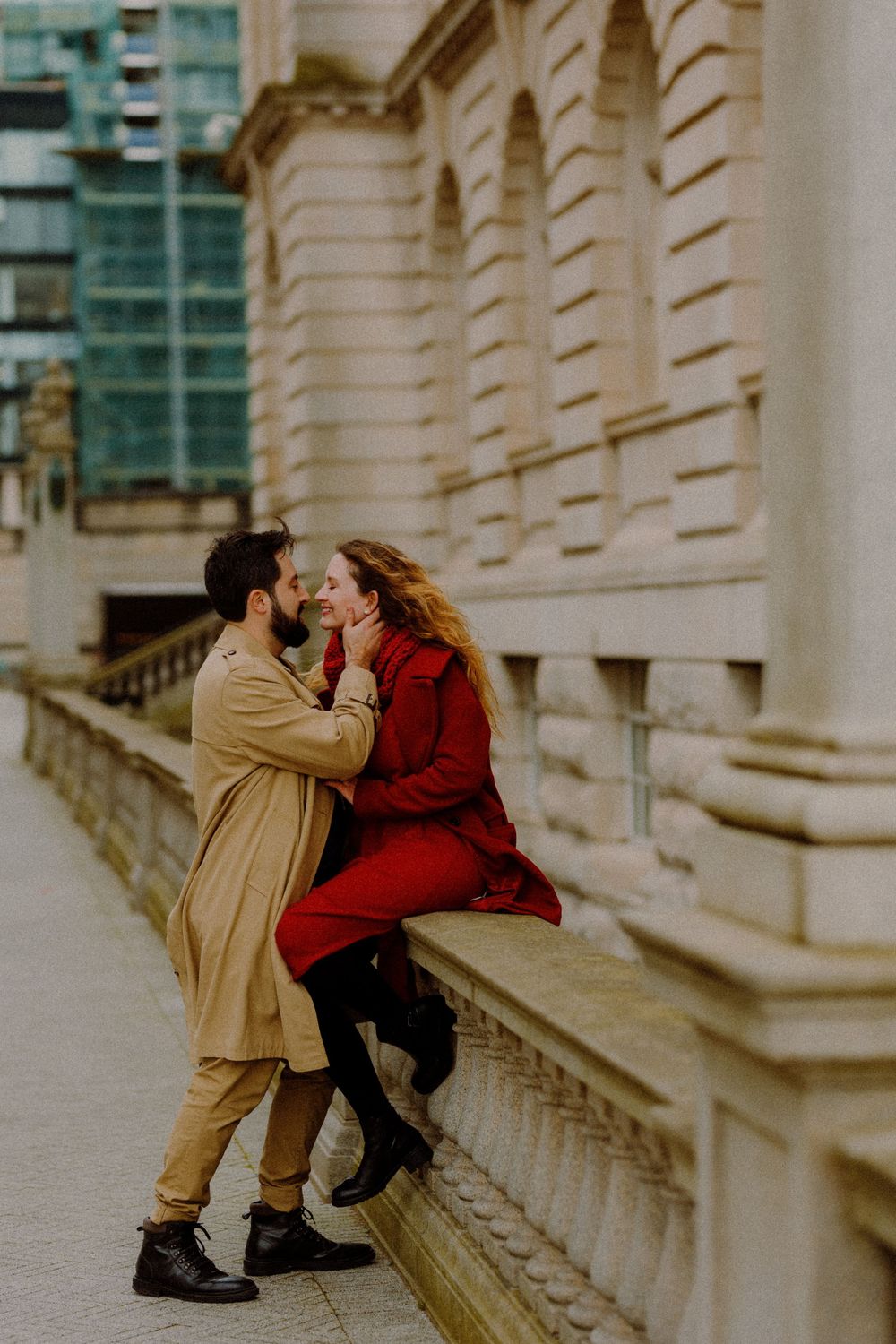Romantic moment captured between couple on stone steps of classical building.