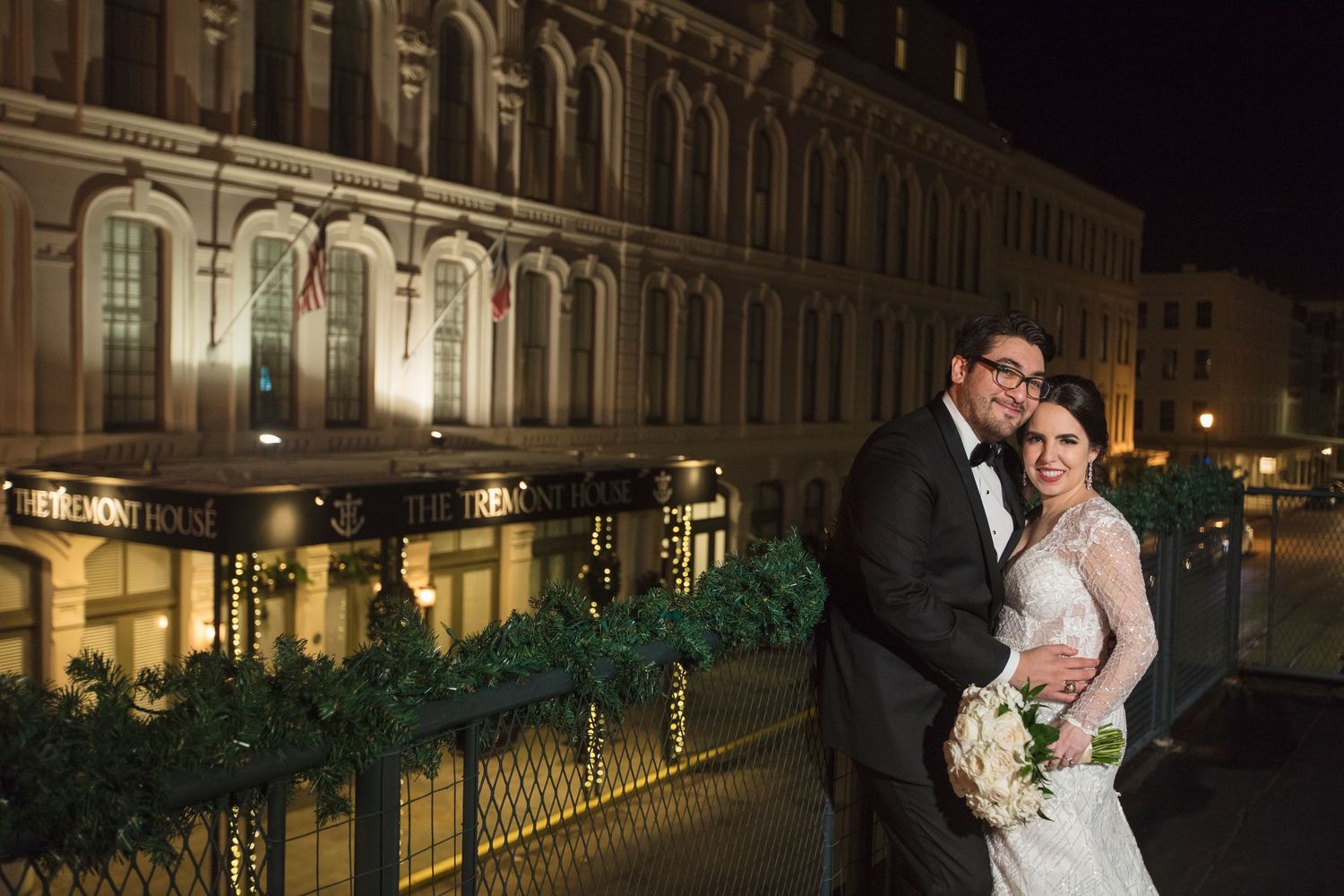 Elegant nighttime portrait in front of historic illuminated building with ornate architecture.