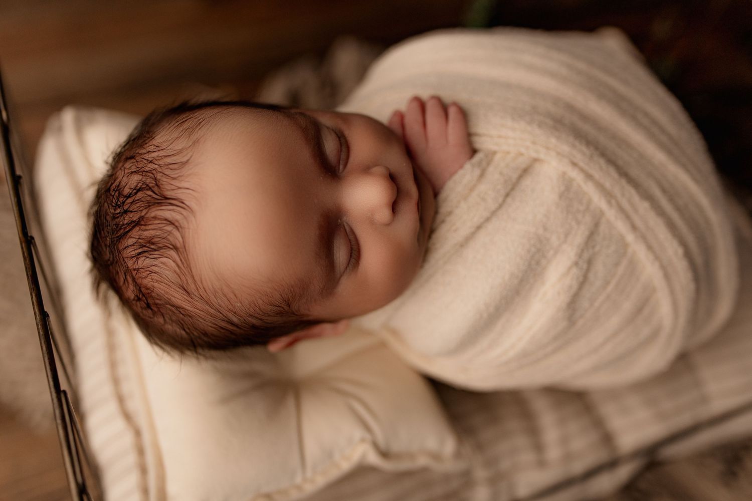 Close-up of peaceful sleeping newborn wrapped in soft white swaddle.