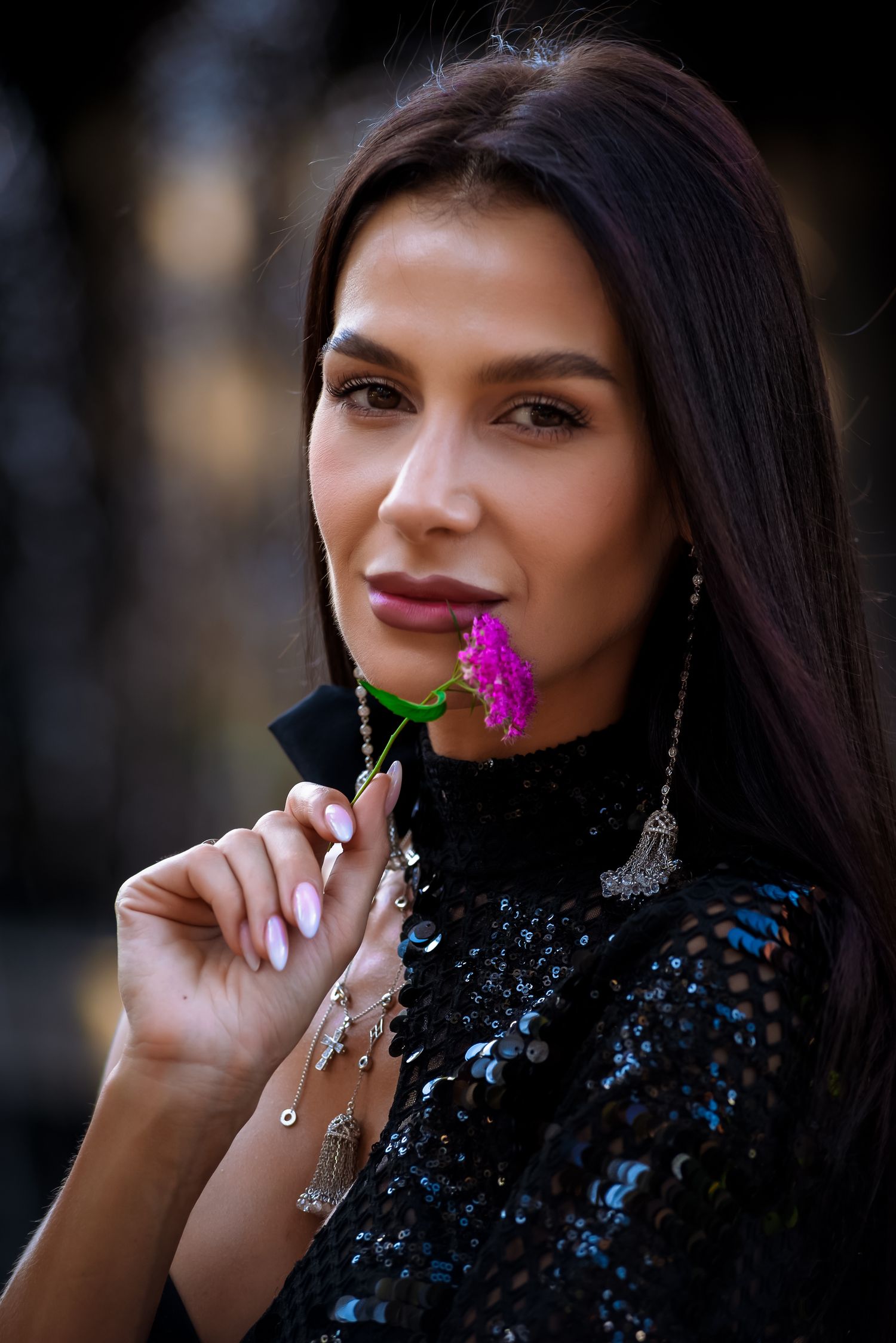 Close-up portrait with delicate purple flowers against dark background.