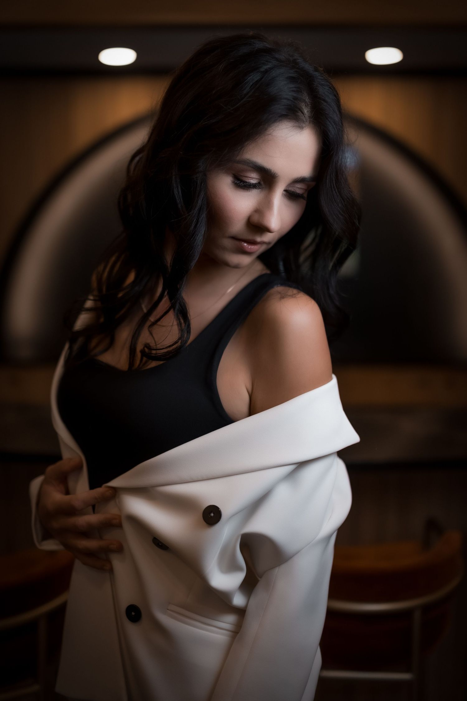 Dramatic portrait series featuring an off-shoulder white garment in moody lighting.