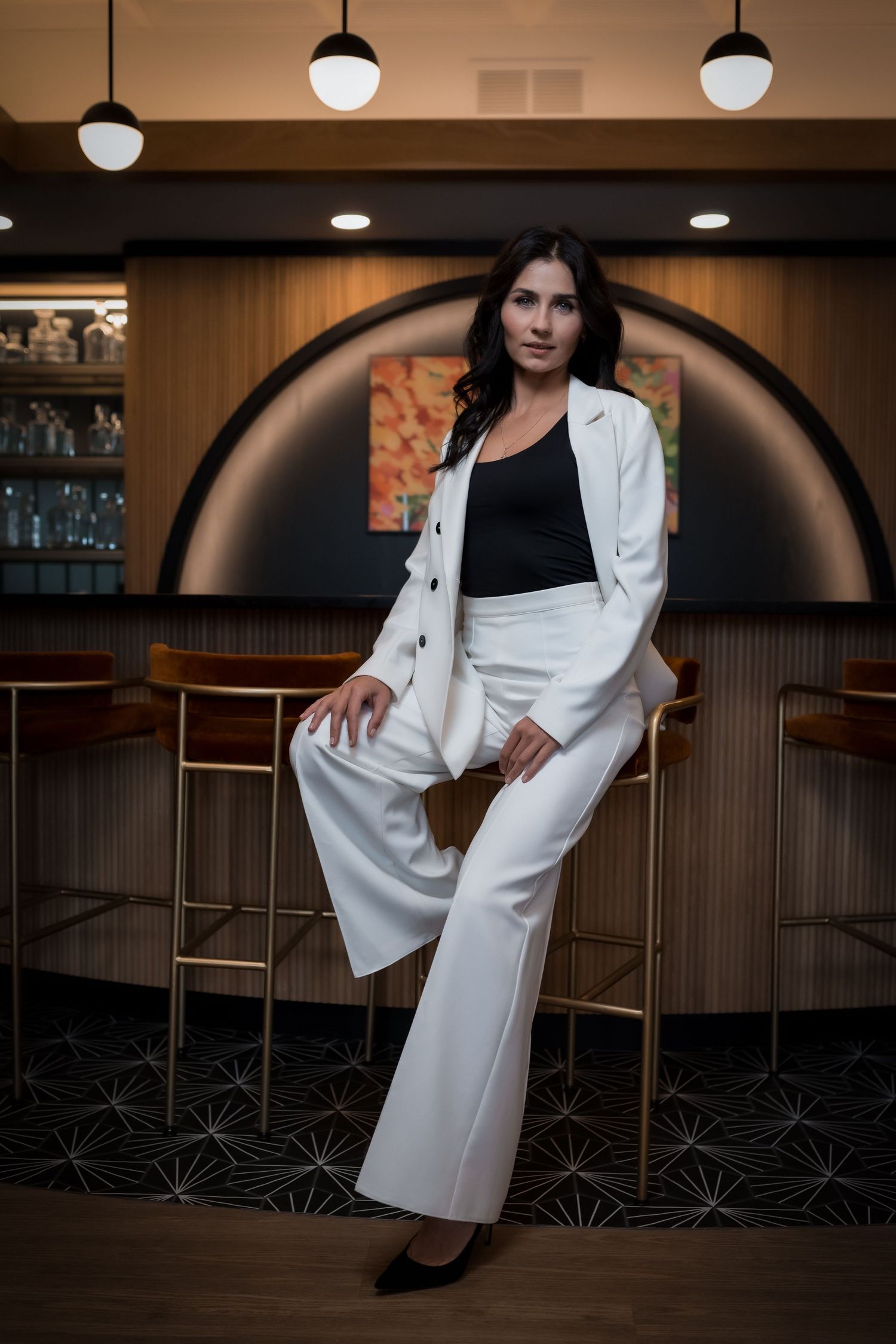 Stylish fashion photography in a bar setting featuring a white blazer and dark interior.