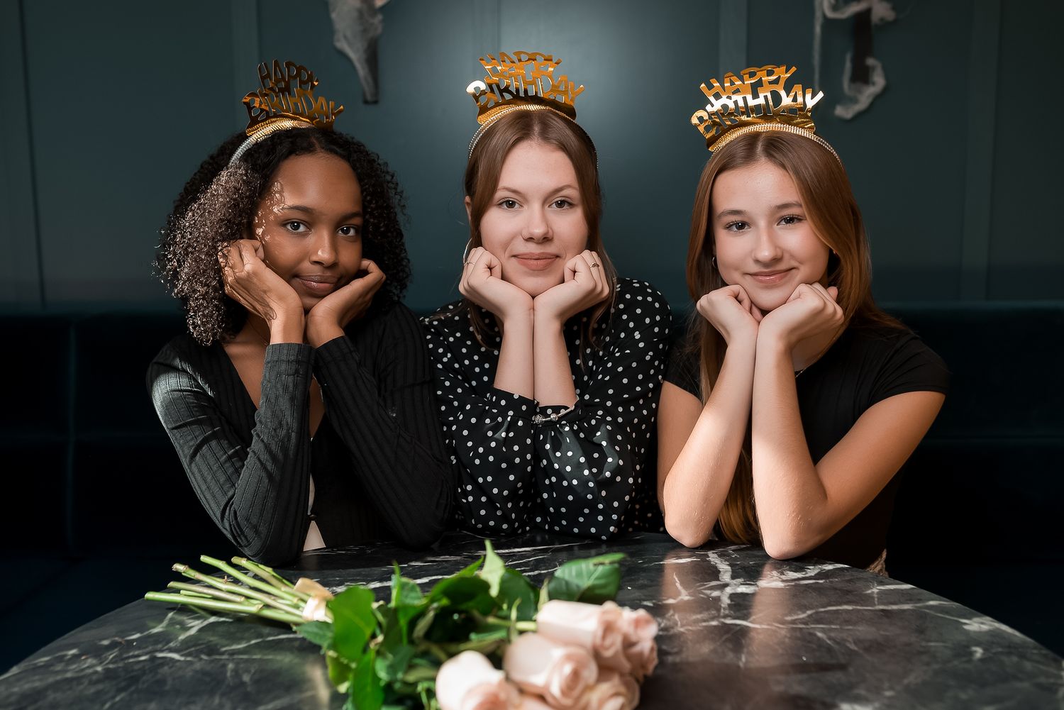 Friends in polka dot dresses posing playfully at a table.