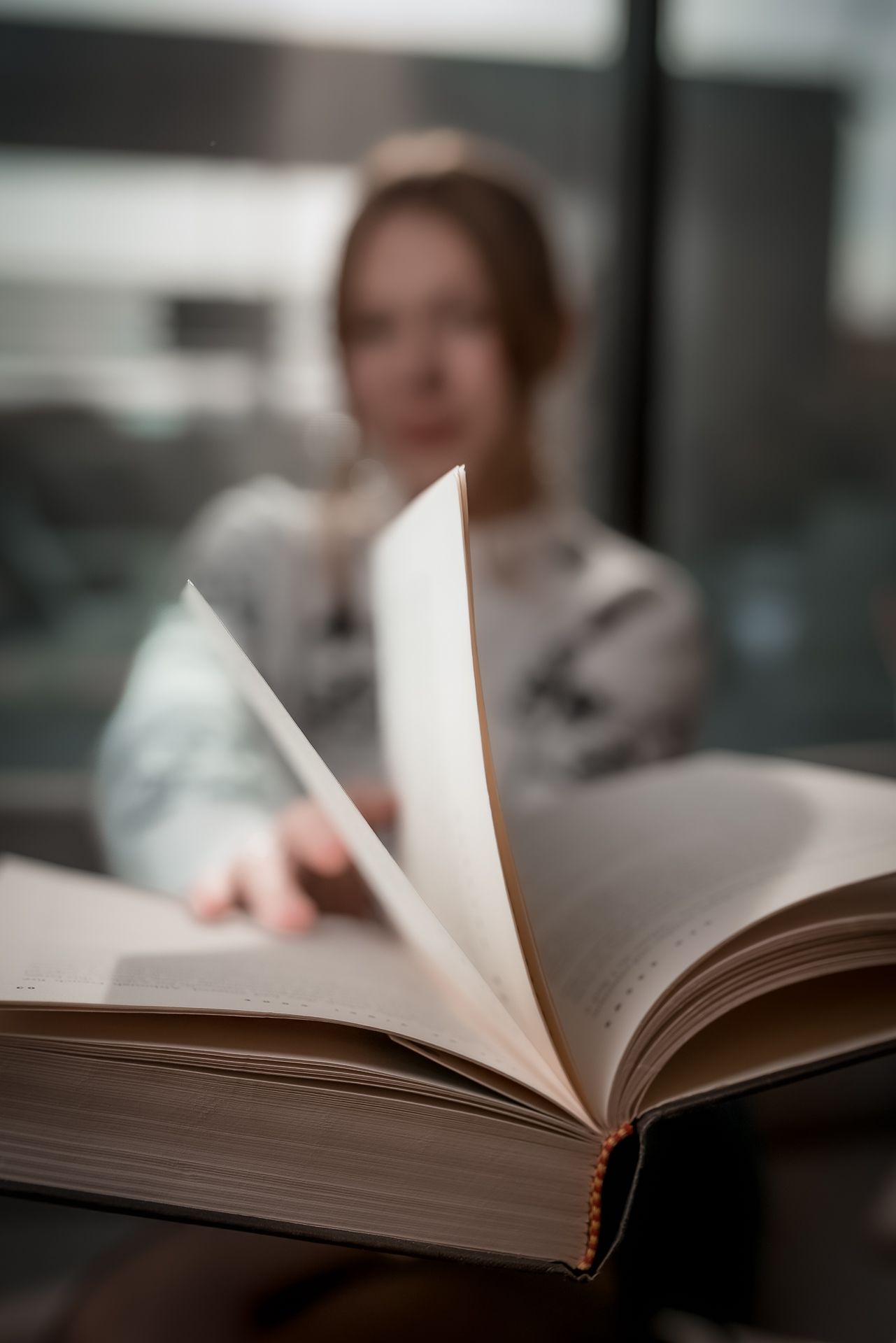 Open book with pages turning against blurred background.