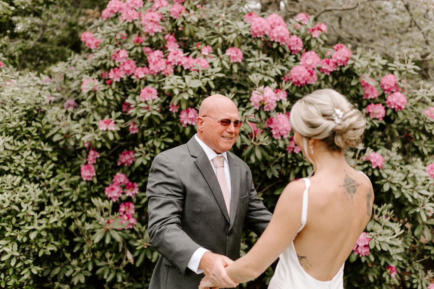 A joyful dance sequence captured in a garden with pink azalea bushes in the background.
