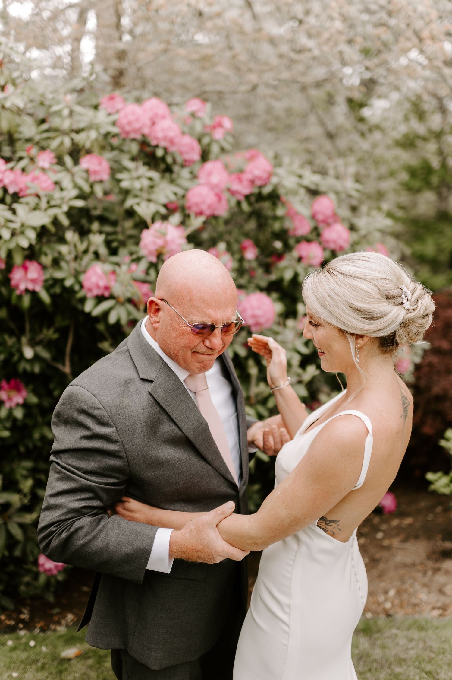 A sweet dance moment between two people surrounded by blooming pink flowers in a garden.