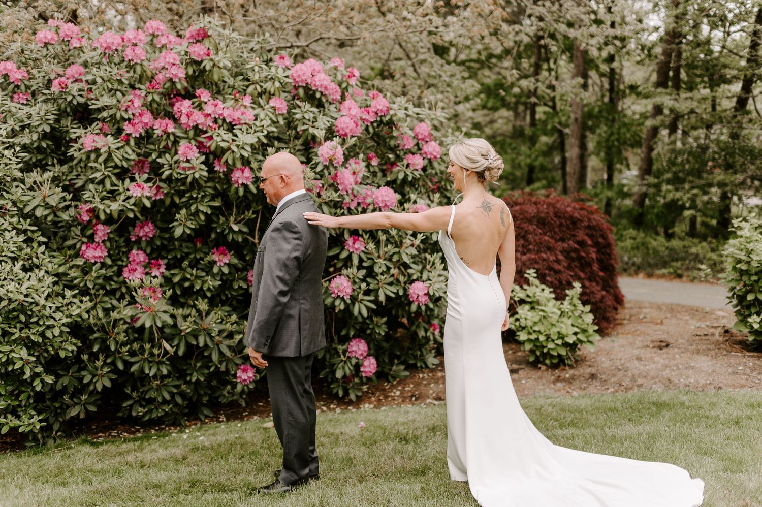 First look moment captured in garden with blooming pink flowers.