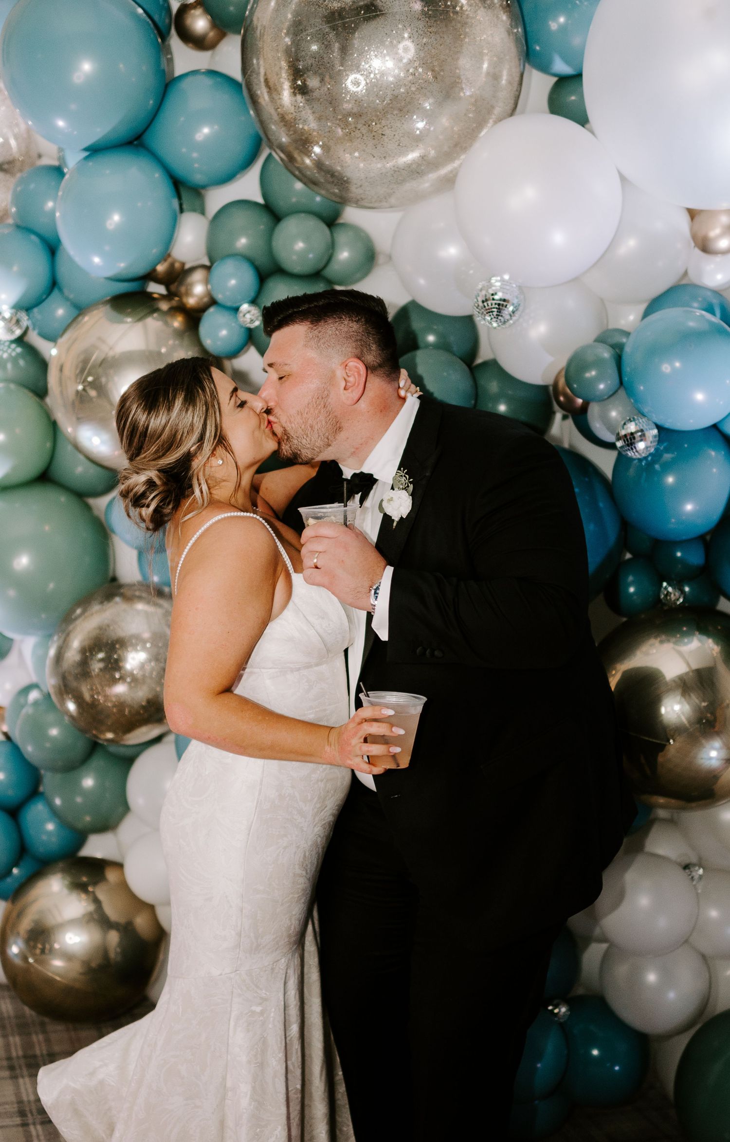 A romantic moment between newlyweds beneath an elegant balloon arch display.